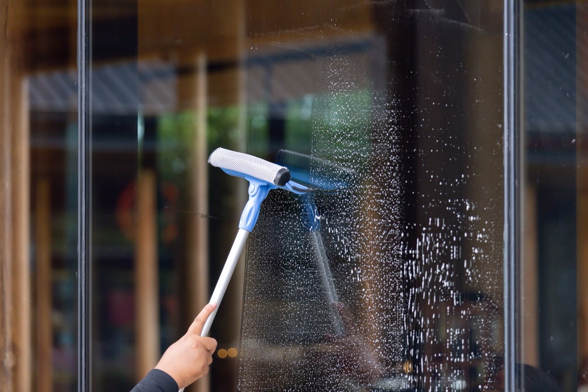 Close-up of a squeegee pulling a clean line down a window pane